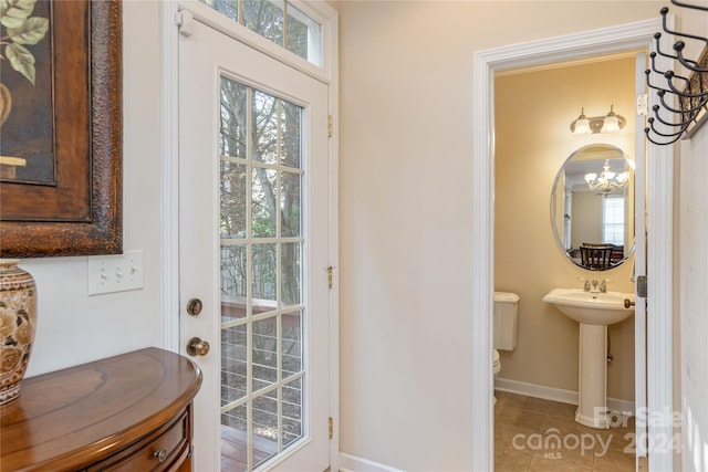 doorway featuring a chandelier, sink, and light tile floors