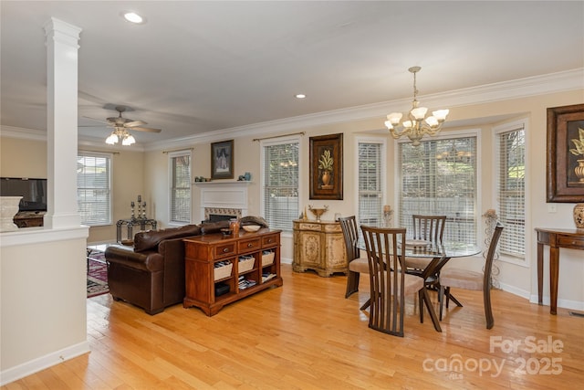 living area with ceiling fan with notable chandelier, light wood-style floors, a fireplace, crown molding, and baseboards