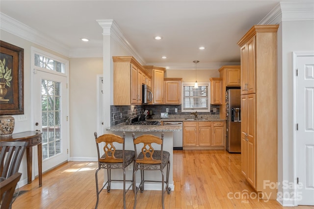 kitchen featuring light stone counters, a peninsula, light wood-style flooring, appliances with stainless steel finishes, and a kitchen breakfast bar