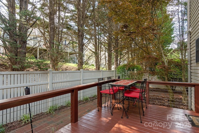 wooden deck with outdoor dining area and a fenced backyard