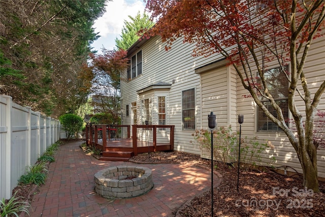 view of patio / terrace featuring a wooden deck, fence private yard, and an outdoor fire pit