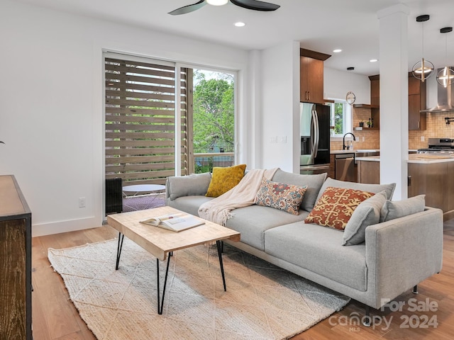 living room with sink, light hardwood / wood-style flooring, and ceiling fan