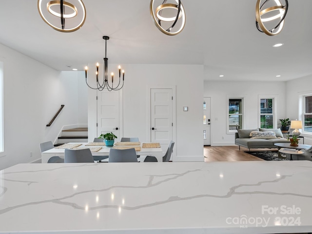 interior space featuring hardwood / wood-style floors, hanging light fixtures, and light stone countertops