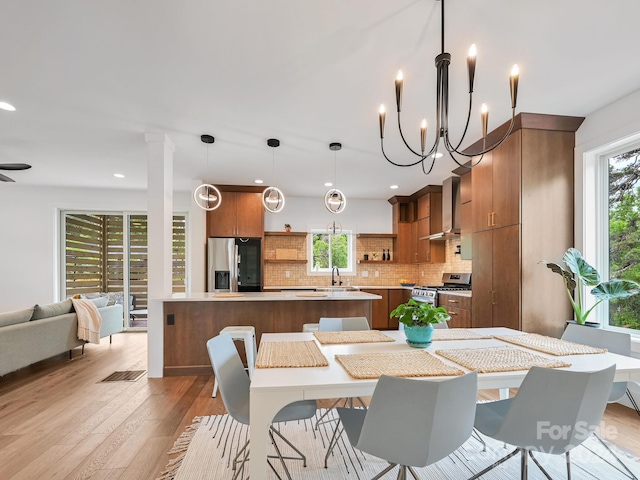 dining area featuring ceiling fan with notable chandelier and light hardwood / wood-style floors