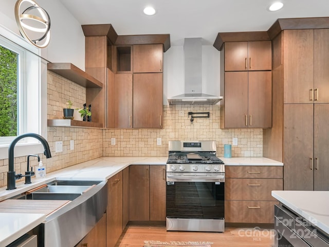 kitchen featuring light hardwood / wood-style flooring, tasteful backsplash, wall chimney range hood, and gas range