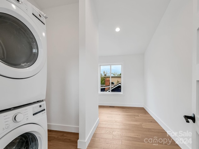 clothes washing area featuring hardwood / wood-style flooring and stacked washer and dryer