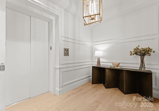 home office with elevator, light hardwood / wood-style flooring, and a chandelier