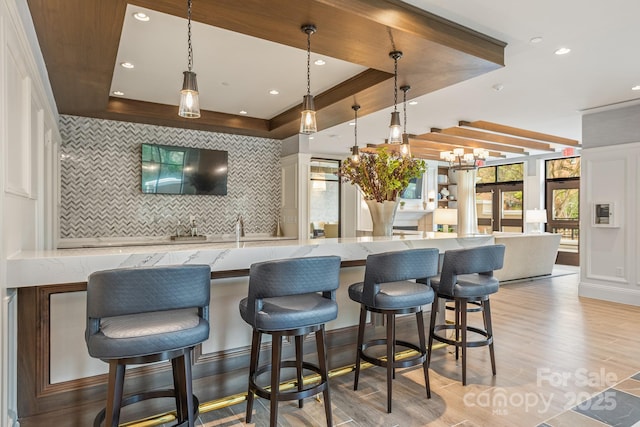 kitchen with tasteful backsplash, a raised ceiling, a kitchen breakfast bar, and hanging light fixtures