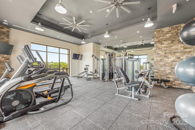 workout area featuring a raised ceiling and ceiling fan