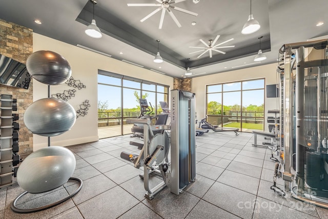 gym featuring a raised ceiling and ceiling fan