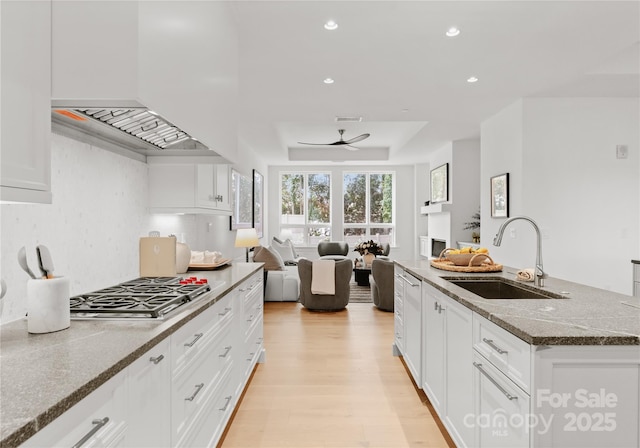 kitchen with stone counters, white cabinetry, stainless steel gas stovetop, and an island with sink