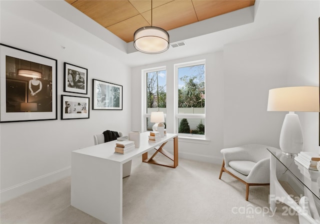 office area with a raised ceiling, wooden ceiling, and light carpet