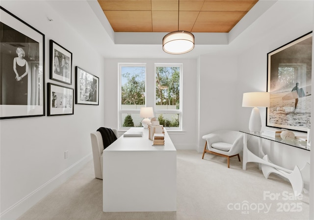 carpeted office with wood ceiling and a tray ceiling