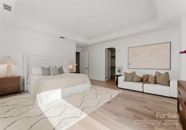 bedroom featuring light hardwood / wood-style floors and a raised ceiling