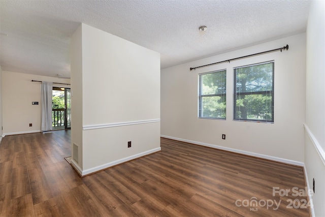 spare room featuring dark hardwood / wood-style floors and a textured ceiling