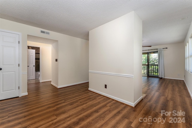 empty room with dark hardwood / wood-style flooring and a textured ceiling