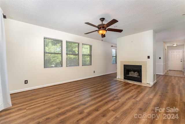 unfurnished living room featuring a fireplace, a textured ceiling, and dark hardwood / wood-style floors