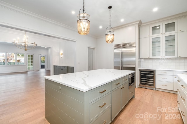 kitchen with hanging light fixtures, beverage cooler, a kitchen island, light wood-type flooring, and gray cabinets