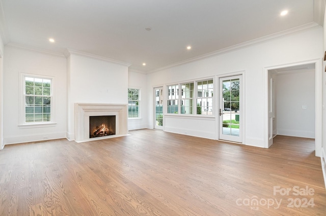 unfurnished living room featuring light hardwood / wood-style flooring, ornamental molding, and a wealth of natural light