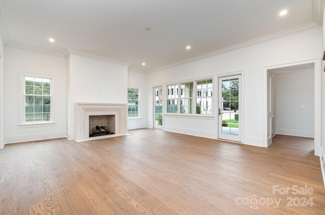 unfurnished living room featuring light hardwood / wood-style flooring, ornamental molding, and a healthy amount of sunlight