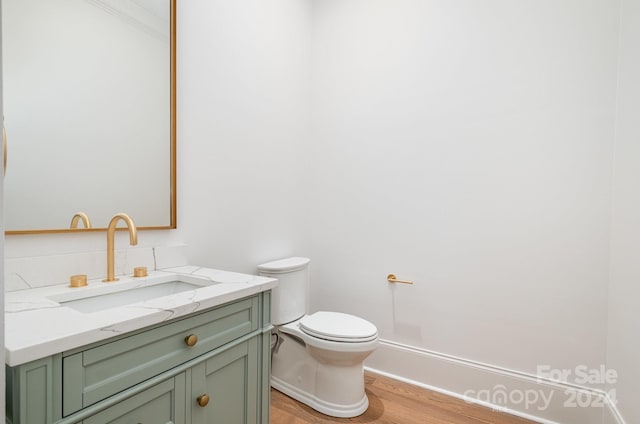 bathroom with toilet, hardwood / wood-style floors, and vanity