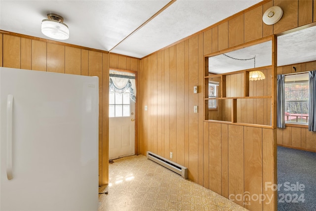 kitchen with a baseboard heating unit, wood walls, and white fridge