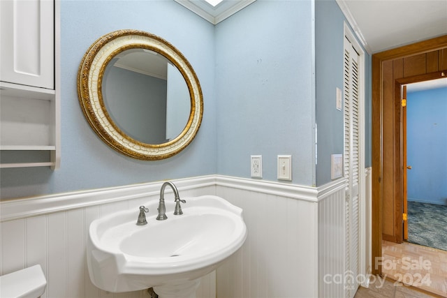 bathroom with crown molding, tile flooring, toilet, and sink