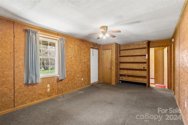 spare room featuring a textured ceiling, ceiling fan, and dark carpet