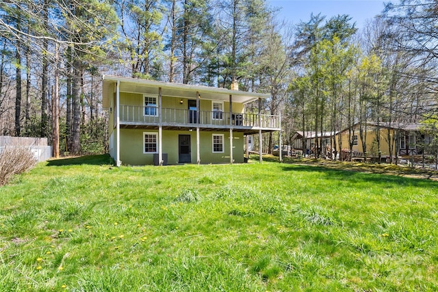 rear view of property featuring a lawn and a balcony