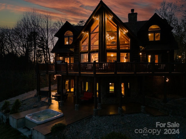 back house at dusk featuring an outdoor hot tub and a patio area