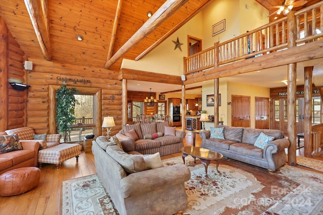 living room with log walls, a wealth of natural light, high vaulted ceiling, and light hardwood / wood-style floors