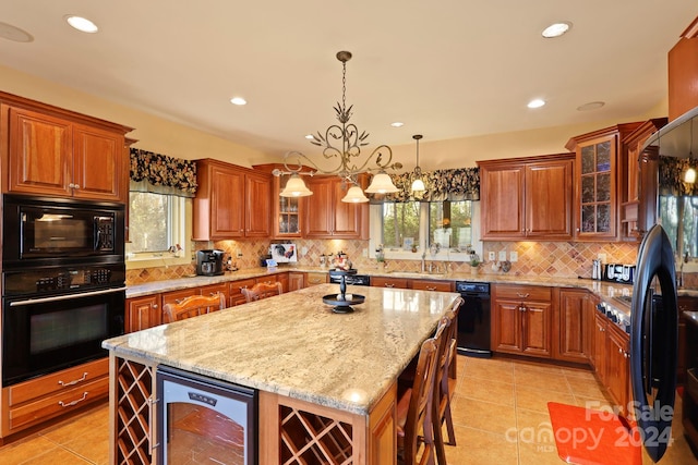 kitchen with a kitchen island, light tile floors, a notable chandelier, beverage cooler, and black appliances