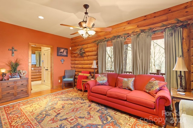 living room with ceiling fan, light wood-type flooring, and rustic walls