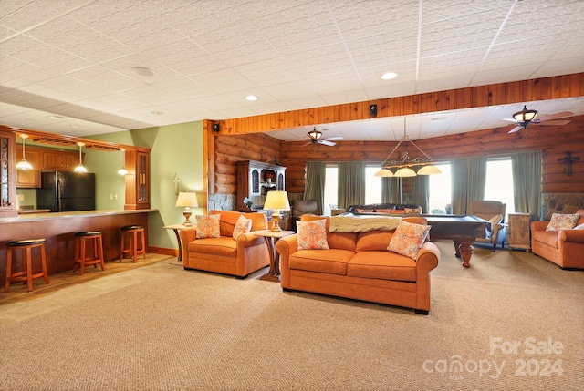 carpeted living room featuring ceiling fan, bar area, and rustic walls