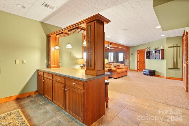 kitchen featuring ceiling fan, hanging light fixtures, light colored carpet, and kitchen peninsula