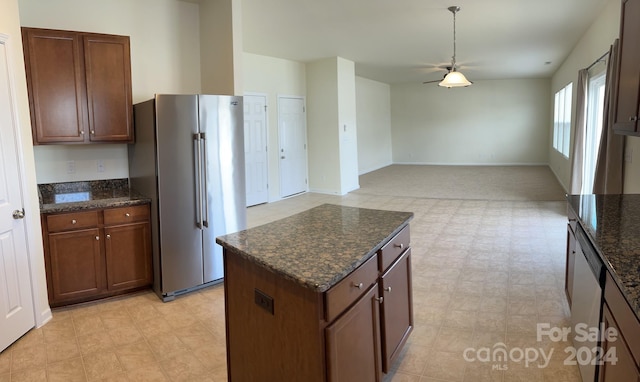 kitchen featuring dark stone counters, a center island, stainless steel appliances, and light tile floors