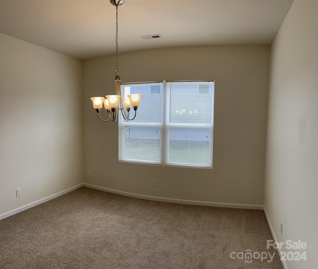 unfurnished room featuring dark colored carpet and a chandelier