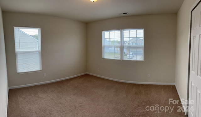 empty room featuring dark colored carpet and plenty of natural light