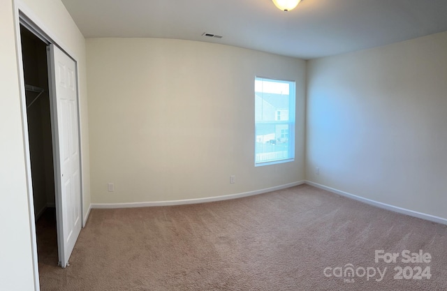 unfurnished bedroom featuring light carpet and a closet