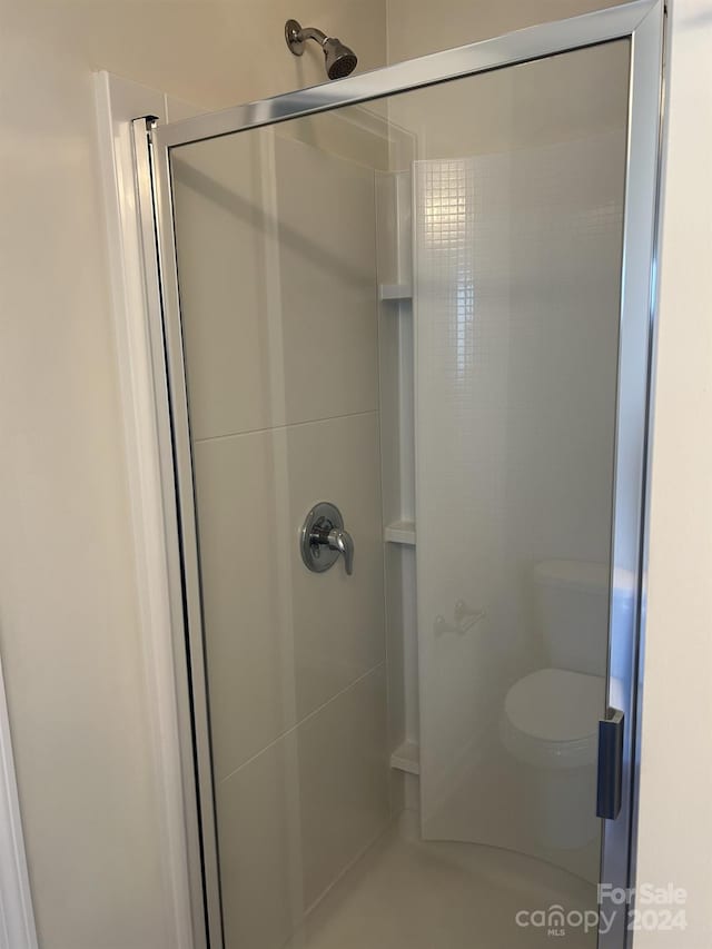 bathroom featuring toilet and a shower with shower door