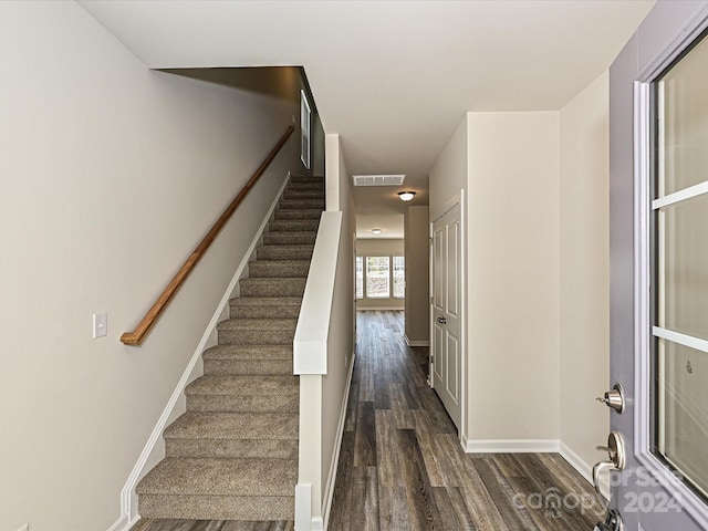 staircase with baseboards, visible vents, and wood finished floors