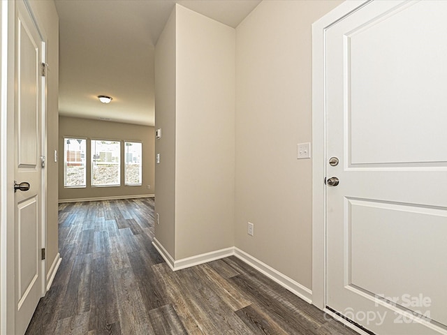 corridor featuring dark wood-type flooring and baseboards