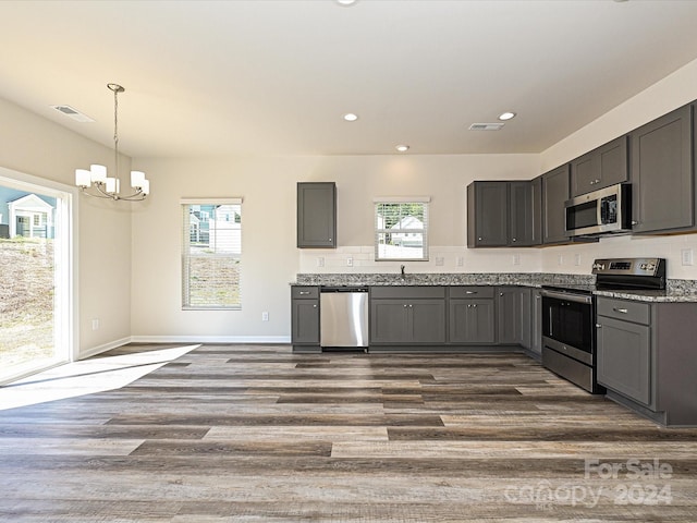 kitchen with dark hardwood / wood-style floors, stainless steel appliances, hanging light fixtures, and gray cabinetry