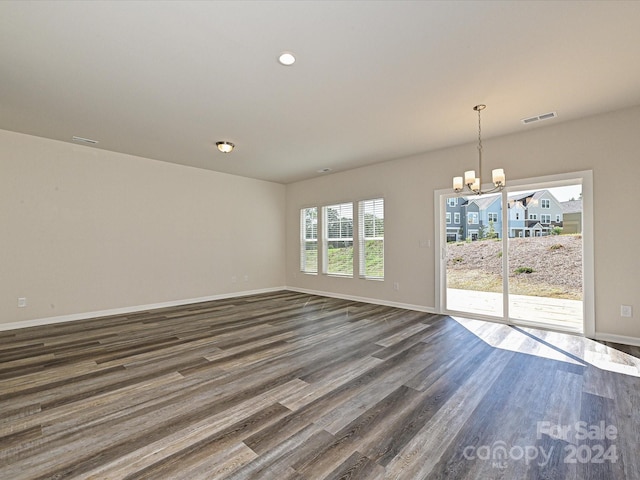 spare room featuring dark wood-style flooring, recessed lighting, visible vents, an inviting chandelier, and baseboards