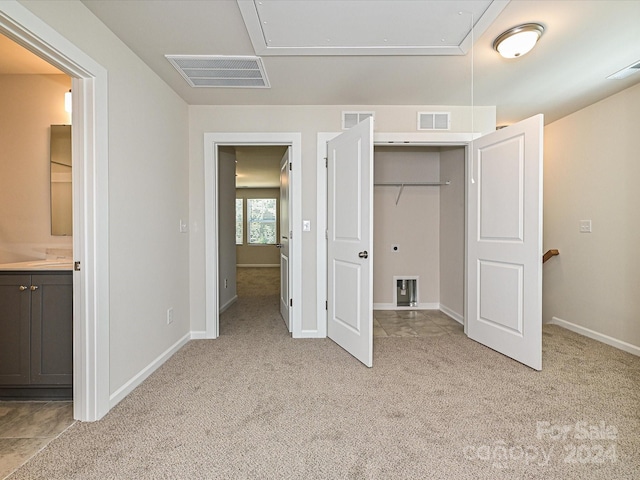 unfurnished bedroom featuring connected bathroom, light colored carpet, and a closet