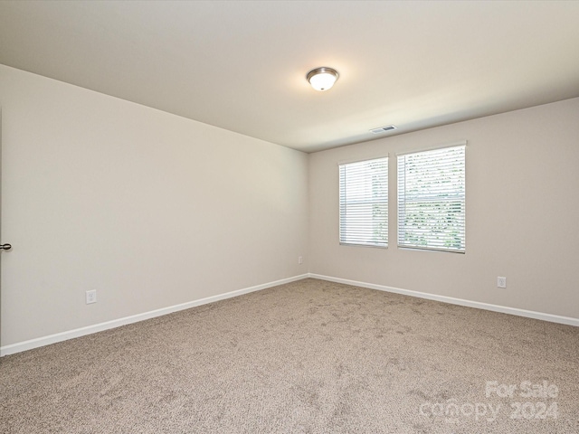 spare room featuring carpet floors, baseboards, and visible vents