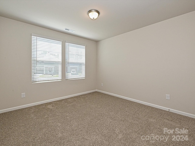 carpeted spare room featuring visible vents and baseboards