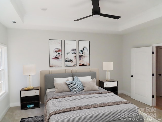 bedroom with ceiling fan, light colored carpet, and a raised ceiling