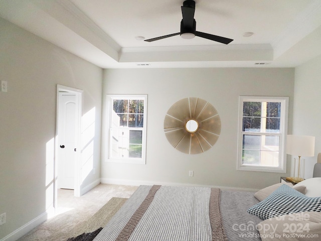 carpeted bedroom featuring ceiling fan, a raised ceiling, and multiple windows