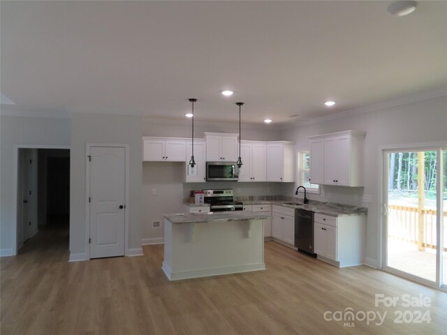 kitchen featuring pendant lighting, appliances with stainless steel finishes, a center island, white cabinetry, and sink